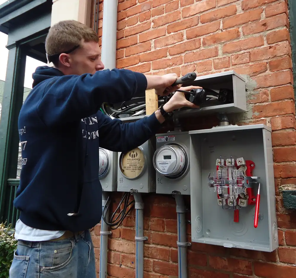 An electrician installing outdoor electric meters on a house