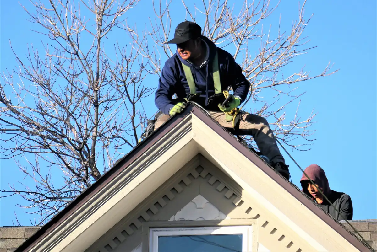 Two roofers working on a house roof